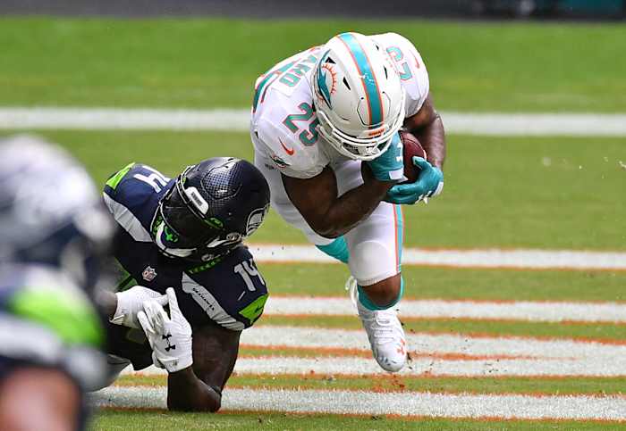 Xavien Howard goes to the ground as he secures an interception in front of Seahawks receiver DK Metcalf during a game in 2020